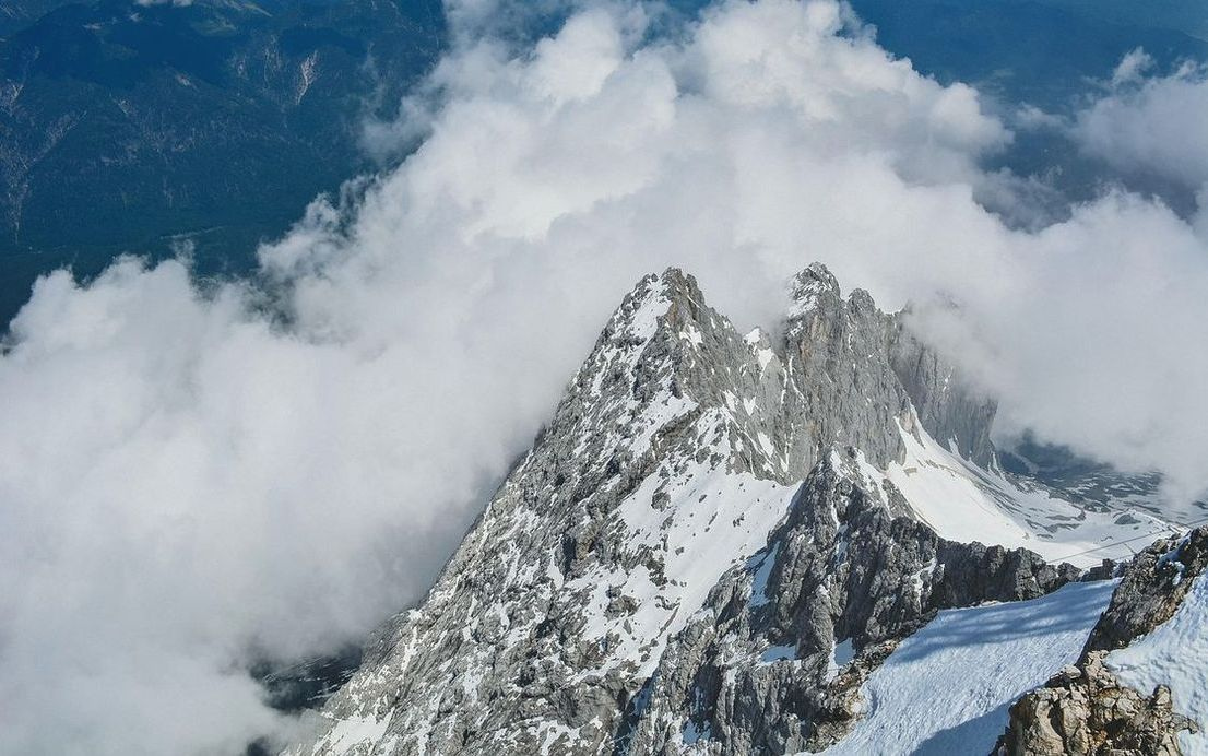 A estrutura metálica da roda gigante contra o céu azul claro, com o parque de diversões abaixo
